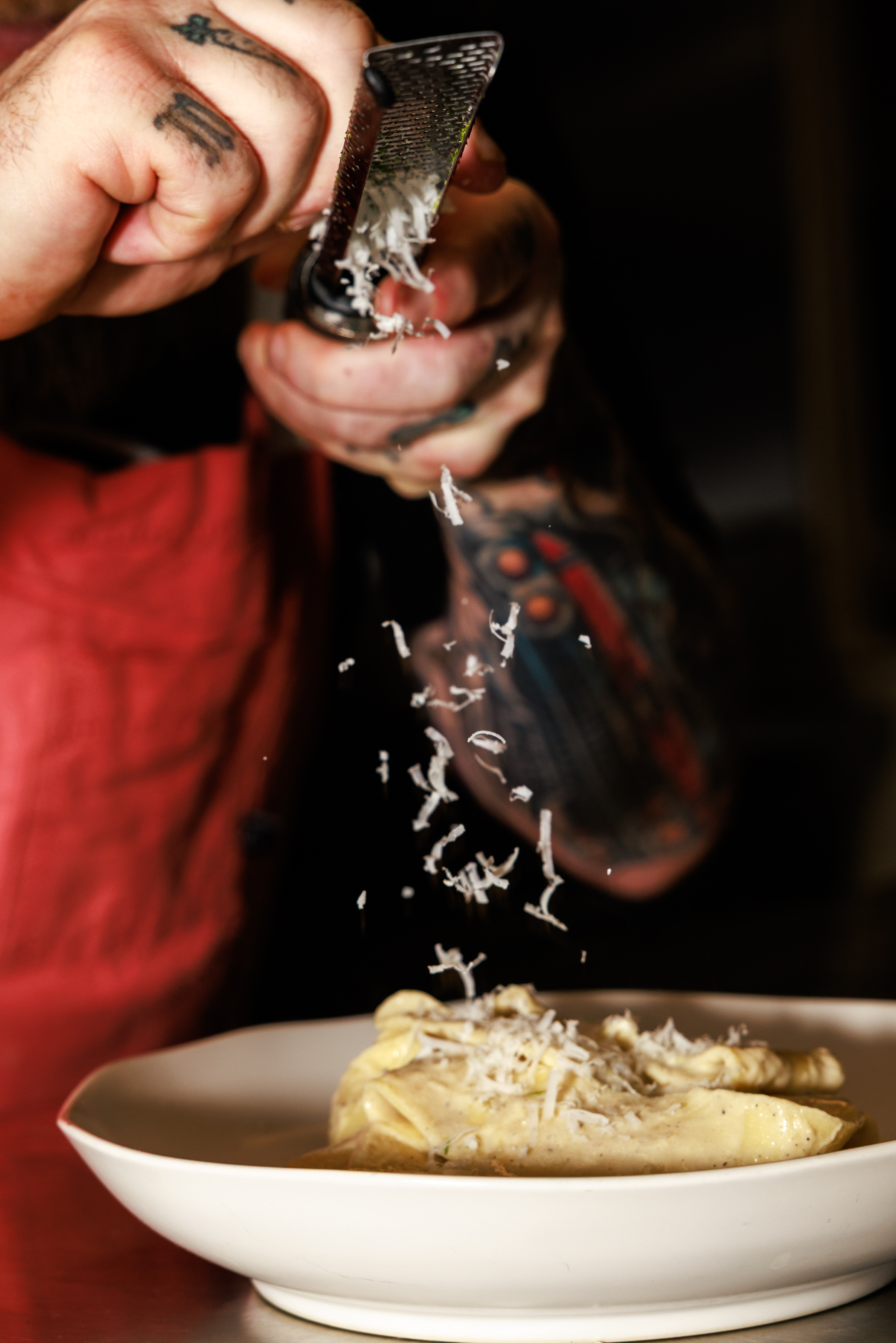 Chef grating truffles over pappardelle