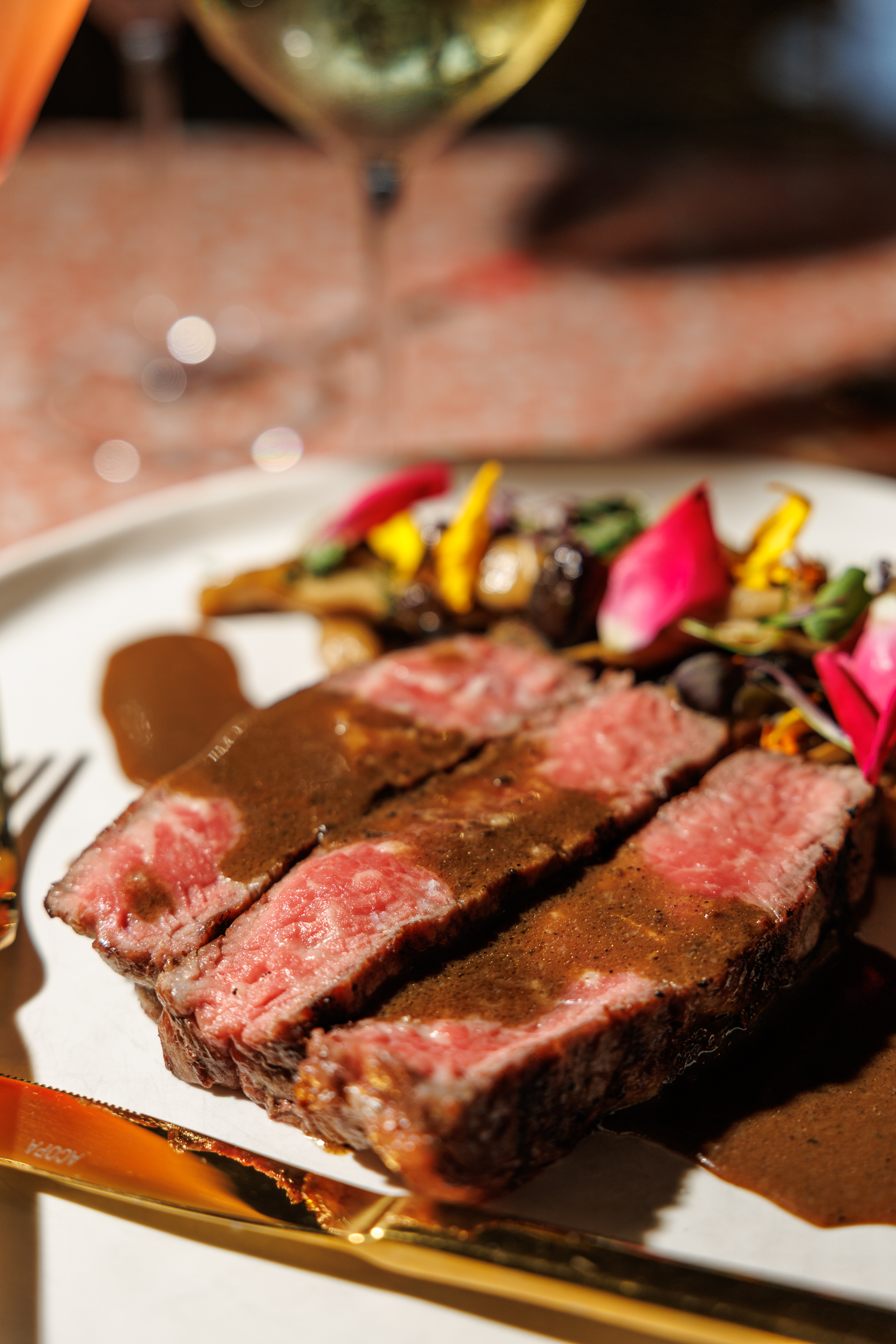 Person enjoying steak and red wine